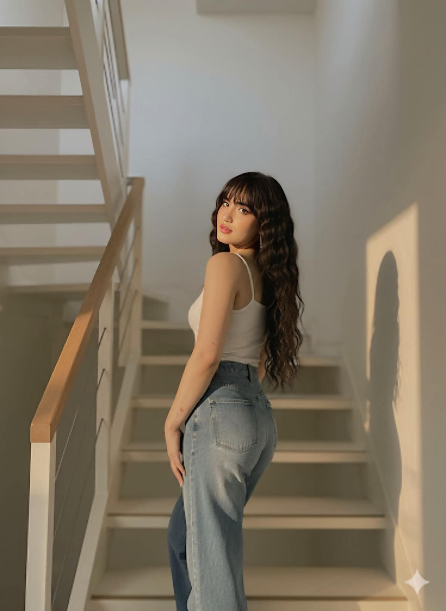 stands on a white stairwell, looking back at the camera